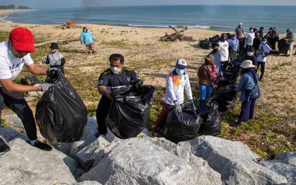 Pelajar bergotong royong mengumpulkan sampah yang telah dikutip.