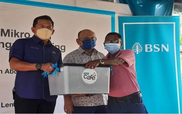 Mohd Shahar (kiri) menyampaikan sumbangan kepada penerima pada Program Bank Simpanan Nasional (BSN) komuniti mikro dan kemudahan Perbankan Sungai Lembing di pekarangan Balai Polis Sungai Lembing, pada Sabtu.