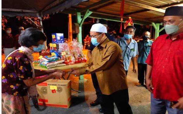 Che Abdullah (dua dari kanan) menyampaikan sumbangan limau dan angpau kepada penduduk pada Majlis Ramah Mesra Bersama Masyarakat Cina Sempena Sambutan Tahun Baharu Cina di Kampung Kulim, Tumpat.