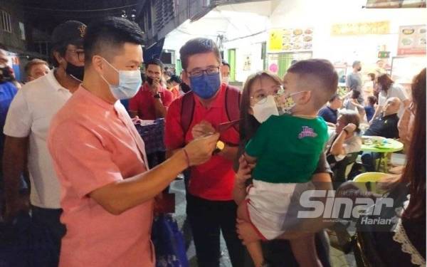 Hock Kuan (kiri) turun padang mengagihkan angpau dan limau kepada masyarakat Tiong Hua, Melayu dan India menjelang sambutan Tahun Baharu Cina di sekitar bandar Kota Bharu sambil diiringi tarian singa.