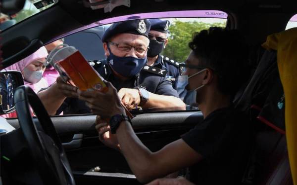 Wan Rukman (kiri) menyampaikan cenderahati kepada pengguna jalan raya pada pelancaran Kempen Keselamatan Jalan Raya sempena Musim Perayaan Tahun Baharu Cina peringkat negeri Terengganu di Plaza Tol Kuala Terengganu, Kampung Gemuroh, pada Isnin, - Foto Bernama 