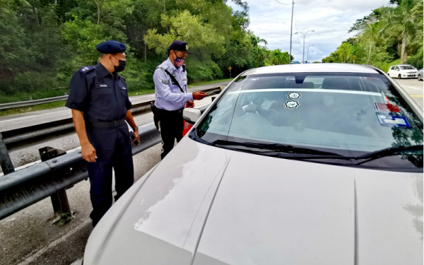 Shafiei (kiri) membuat pemeriksaan kenderaan yang melalui Plaza Tol Mambau Lebuhraya Seremban - Port Dickson.