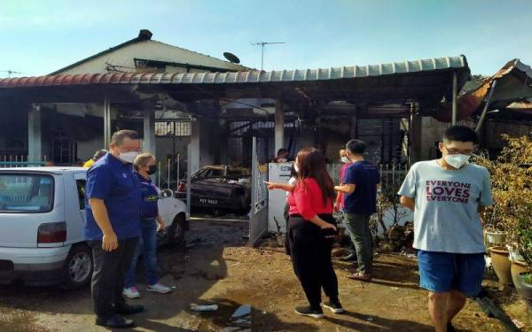 Robert Ling Kui Ee (kiri) melihat kesan kebakaran membabitkan lima buah rumah penduduk di Taman Intan pada Jumaat.