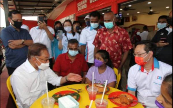 Anwar (kiri) beramah mesra dengan masyarakat setempat semasa melakukan 'walkabout' di pekan Kelapa Sawit, Kulai pada Jumaat.