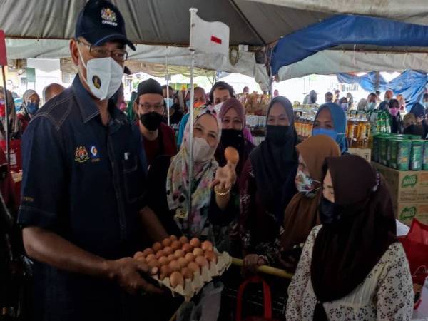 Rosol (kiri) melihat telur yang dibeli oleh pelanggan pada Program Jualan Keluarga Malaysia (PJKM) di Dataran Pasar Tani, Kuala Ping, Kuala Berang pada Sabtu.