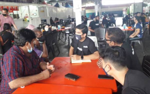 Syed Saddiq (tengah) mendengar permasalahan yang disuarakan wakil pertubuhan bukan kerajaan (NGO) India semasa Kempen Jelajah Mendengar Sempena PRN Johor di Medan Selera Ulu Tiram, pekan Ulu Tiram, Johor Bahru pada Sabtu.