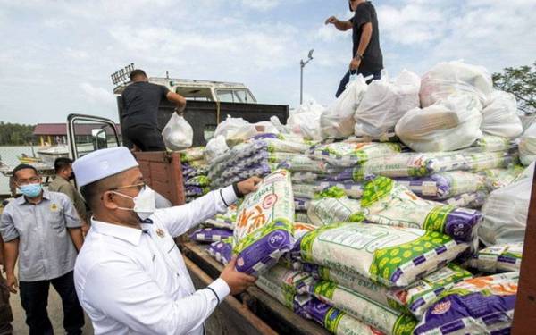 Ahmad Marzuk (dua dari kiri) melihat sebahagian makanan keperluan harian yang akan diagihkan kepada nelayan setempat sempena Majlis Santuni Nelayan DUN Kijang di Kompleks LKIM Kuala Besar di sini pada Ahad. - Foto Bernama