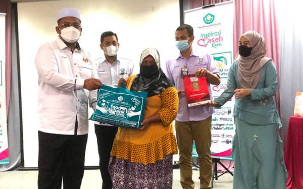 Ahmad Marzuk (kiri) menyampaikan Food Bank daripada Yayasan Pembangunan Ekonomi Islam Malaysia (YaPEIM) kepada penerima, Rosnani Mat Riah, 42, (tengah).