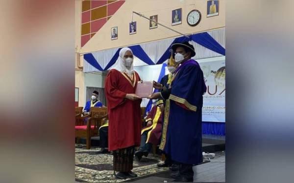 Muhammad Azwan (kanan) menyampaikan sijil kepada salah seorang pelajar pada Majlis Graduasi ke-17 di Dewan Sri Gemilang, MRSM Besut pada Ahad.