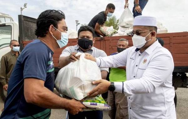 Ahmad Marzuk (kanan) menyampaikan makanan keperluan harian kepada nelayan setempat sempena Majlis Santuni Nelayan DUN Kijang di Kompleks LKIM Kuala Besar di sini pada Ahad. - Foto Bernama
