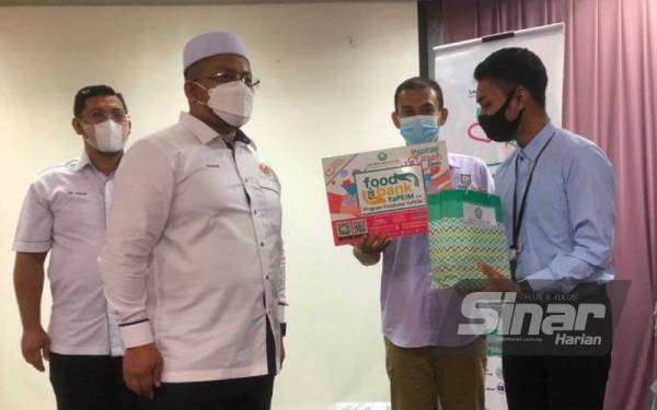 Ahmad Marzuk (dua, kiri) menyampaikan makanan sedia untuk dimakan kepada seorang penuntut Diploma Psikologi Kolej Uniti Kota Bharu, Mohamad Shahrul Adnan (kanan).