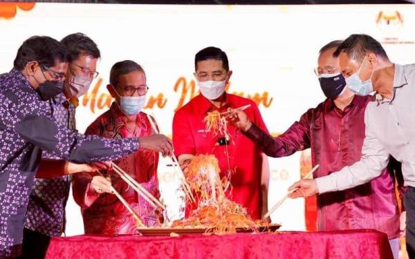 Mohamed Azmin (tengah) menggaul yee sang pada Makan Malam Tahun Baharu Cina bersama Dewan Perniagaan Cina Batu Pahat di Batu Pahat pada malam Isnin.