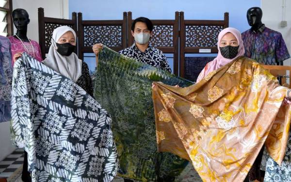 Tiga usahawan batik Norazizah (kanan), Mohd Shawal dan Suhaila menunjukkan batik 'clay marble', batik 'skrin marble dan clay' dan batik 'skrin marble' yang dihasilkan mereka semasa ditemui di Kompleks Kraftangan Malaysia Cawangan Terengganu, Chendering pada Rabu. - Foto Bernama