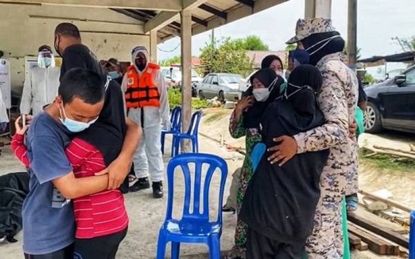 Anak-anak Mohd Ayob berpelukan sambil ditenangkan anggota Maritim setelah jasad bapa mereka dibawa naik ke darat.