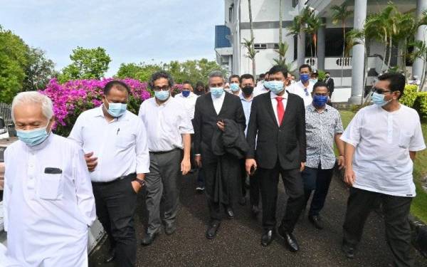 Mohamad Ali (tengah) dan Mohd Hafarizam berjalan bersama penyokong mereka ketika di Mahkamah Melaka, di sini pada Jumaat.