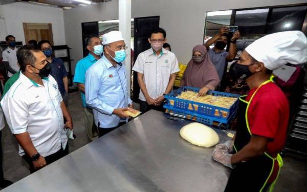 Idris (dua dari kiri) bertanyakan sesuatu dengan usahawan asnaf Mohd Khaizuan (kanan) pada Majlis Penyampaian Bantuan Perniagaan Kepada Usahawan Asnaf di Kampung Masjid Raja, Chendering pada Jumaat. - Foto Bernama