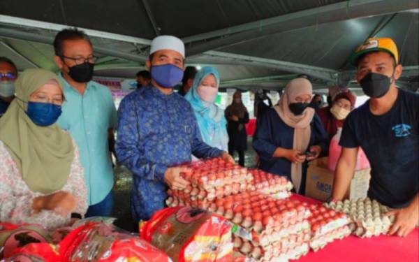 Nik Muhammad Zawawi (tiga dari kiri) menunjukkan telur yang dijual padaProgram Jualan Keluarga Malaysia (PJKM) di Bandar Baharu Pasir Puteh pada Sabtu.