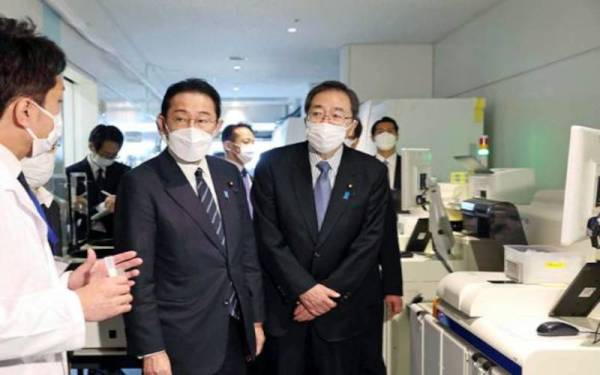 Fumio Kishida (tengah) mendengar penerangan pegawai di pusat kuarantin di Lapangan Terbang Haneda, Tokyo. - Foto AP