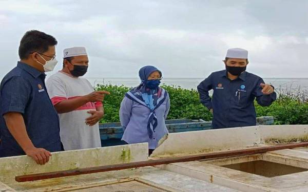 Nik Muhammad Zawawi (kanan) meninjau permasalahan yang dialami golongan nelayan di Kampung Pachakan, Pasir Puteh pada Ahad.