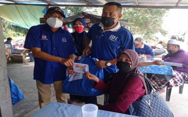 Mohd Youzaimi (kiri) menyerahkan sumbangan kepada penerima dalam Program Sarapan Percuma di Kampung Penyabong, Mersing, pada Ahad.