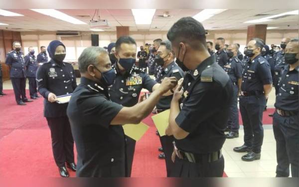 Ramli (kiri) diiringi Mohd Yusri memakaikan pangkat kepada salah seorang pegawai rendah pada Majlis Pemakaian Pangkat Pegawai Rendah Polis di IPK Pahang di Kuantan pada Selasa.