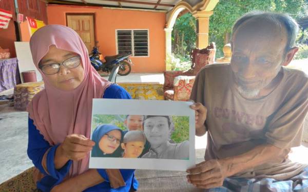 Zaleha dan suaminya menunjukkan gambar Muhammad Fikri (kanan) bersama ibu dan dua lagi adik-beradiknya semasa ditemui di rumahnya di Kampung Teluk Rhu, Sabak Bernam pada Selasa.