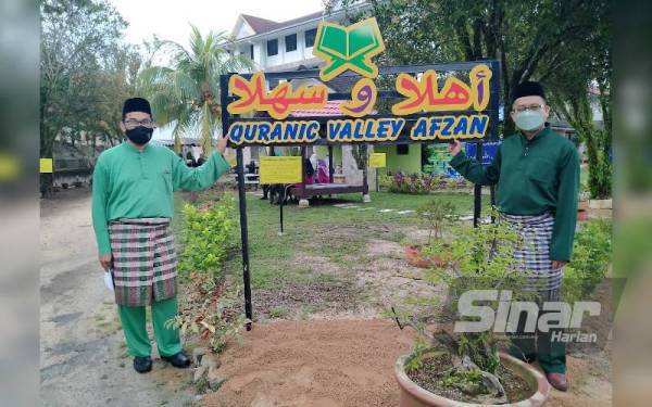 Rozamli (kanan) bergambar di papan tanda utama Quranic Valley Afzan pada majlis pelancaran laman itu Jumaat lalu.