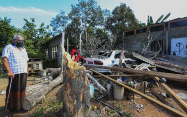 Mohd Zin (kiri) bersama Mohd Aminudin melihat keadaan keretanya yang rosak.