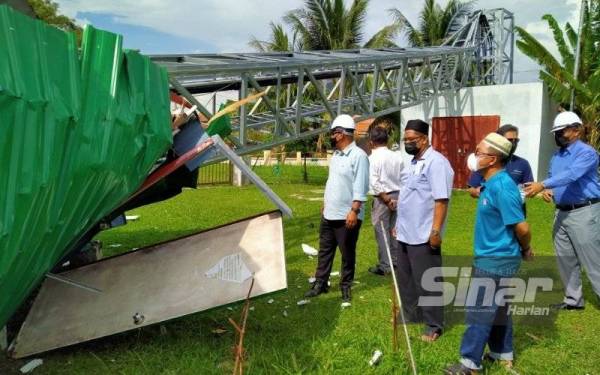 Khairul Shahril (kiri) bersama ahli jawatankuasa surau meninjau keadaan menara telekomunikasi tumbang akibat ribut pada Isnin.