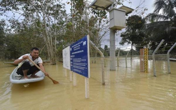 Penduduk setempat Mohamad Rusdi Mohamad Khatib, 34, meninjau keadaan stesen siren amaran awal banjir yang masih digenangi banjir. - Foto Bernama