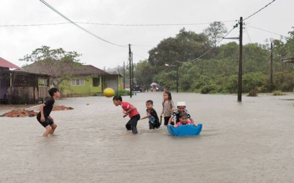 Sekumpulan kanak-kanak bermain air di hadapan rumah yang dinaiki air di daerah Hulu Terengganu.