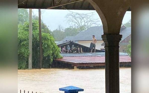 Antara penduduk yang terperangkap memanjat bumbung rumah di Kampung Lubuk Pait, Hulu Terengganu.- Foto ihsan pembaca