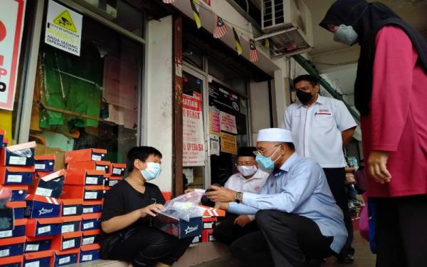 Idris (duduk dari kanan) beramah mesra dengan penerima sumbangan pada Majlis Penyampaian Bantuan Persekolahan Kawasan Bukit Gantang 2022 di Pusat Khidmat Pas Parlimen Bukit Gantang, Taiping pada Ahad.