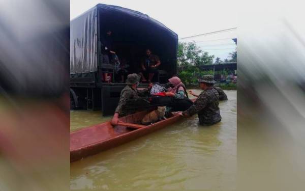 Anggota Briged Kelapan Infantri Malaysia memindahkan penduduk yang terkesan dengan banjir di Rantau Panjang.