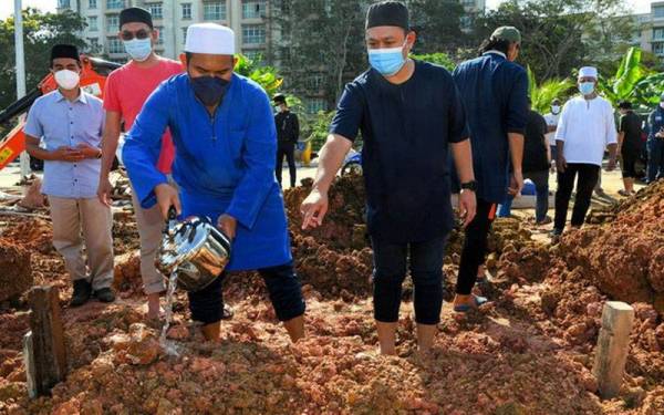 Mohammad Nazrin (kiri) menyiram pusara ayahnya Allahyarham Yahya Atan atau lebih dikenali sebagai ‘Pakya’ selepas dikebumikan pada 10.15 pagi di Tanah Perkuburan Islam Ar Raudah, Taman Mount Austin pada Isnin. Foto: Bernama