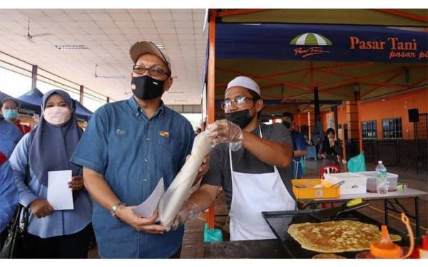 Peniaga turut mengambil peluang merakam gambar bersama Izham (kiri) semasa Program Jualan Prihatin Rakyat.
