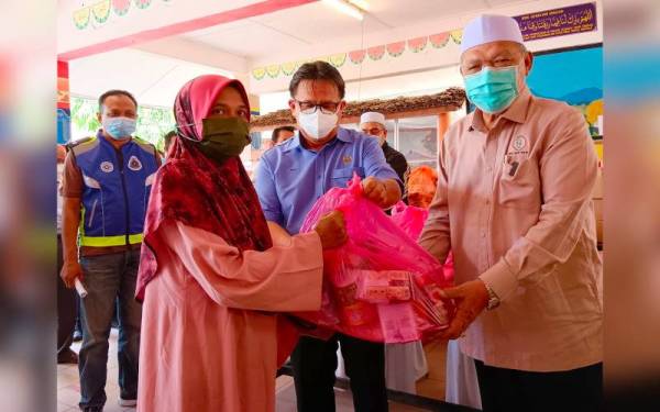 Ahmad (kanan) menyampaikan sumbangan kepada mangsa banjir semasa turun padang melawat mangsa banjir di SK Lati, Pasir Mas pada Isnin.