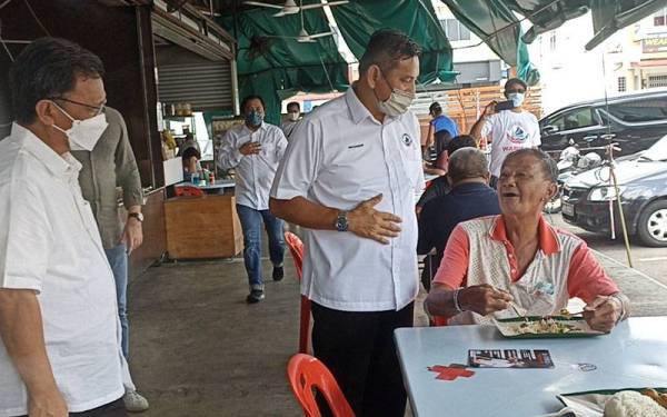 Hishamuddin (tengah) berbual menggunakan bahasa Mandarin ketika berkempen di Pekan Nanas pada Isnin.