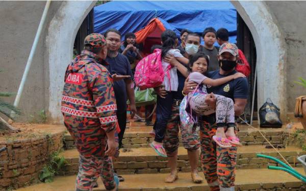 Anggota Jabatan Bomba dan Penyelamat Malaysia (JBPM) membantu memindahkan 68 peserta dan ahli keluarga termasuk 20 kanak-kanak yang menyertai kem solat di Kem Rekreasi Budi, Kampung Belukar Bukit pada Isnin. - Foto Bernama