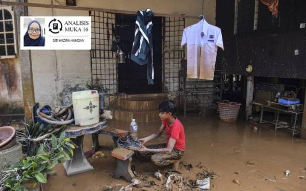 Calon Sijil Pelajaran Malaysia (SPM), Mohd Fakhrul Radzi, 18, melihat kasut sekolahnya yang diselaputi lumpur selepas rumahnya ditenggelami banjir semasa tinjauan di Kampung Padang Tersat.- Foto Bernama
