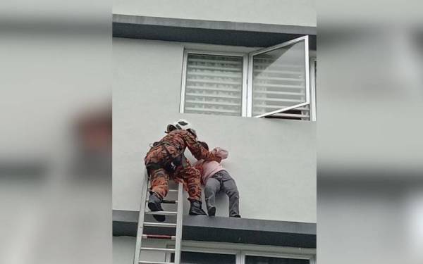 Anggota bomba membantu membawa turun kanak-kanak perempuan yang terperangkap di luar tingkap rumah di tingkat tiga sebuah pangsapuri pada Jumaat. - Foto JBPM Pahang