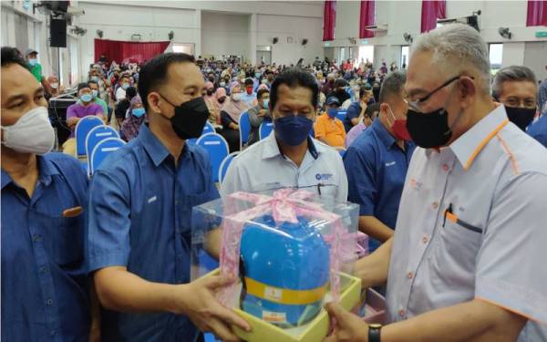 Noh (kanan) menyampaikan simbolik topi keledar kepada guru besar Parlimen Tanjong Karang yang hadir pada Program Back To School Parlimen Tanjong Karang di IPP Tanjong Karang, pada Jumaat.