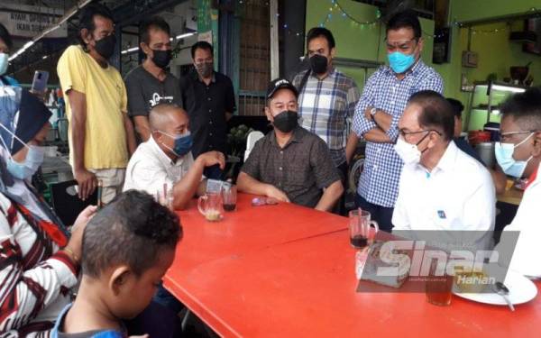 Anwar (dua dari kanan) beramah mesra dengan penduduk setempat dalam progam Santuni dan Sarapan Pagi Bersama Masyarakat Sungai Tiram di Tiram, Johor Bahru, pada Ahad.