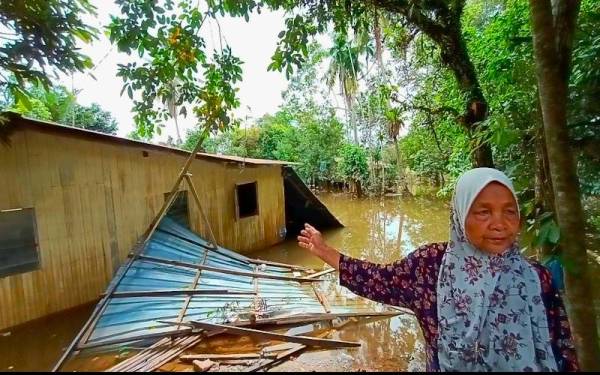 Mariam menunjukkan rumahnya di Kampung Tersang yang musnah akibat dihanyutkan arus banjir.