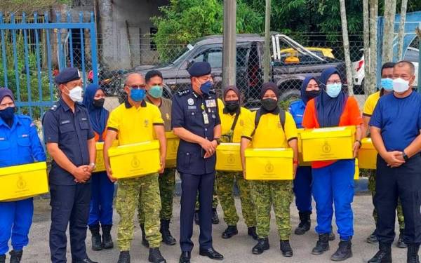 Muhamad Zaki (tengah) menyampaikan sumbangan daripada Tengku Mahkota Kelantan, Dr Tengku Muhammad Faiz Petra kepada anggota keselamatan di Balai Polis Rantau Panjang pada Ahad.