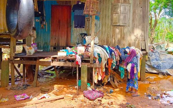 Zawiah memungut pakaian yang ditenggelami banjir untuk dijemur selepas rumahnya di Kampung Tersang dinaiki air.