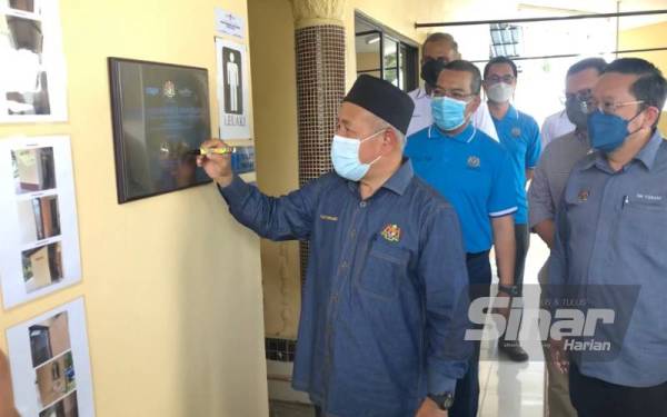 Tuan Ibrahim (kiri) menandatangani plak Perasmian dan Penyerahan Projek Menaik Taraf Fasiliti Tandas di Madrasah Haji Junoh, Kampung Paya Keranji di Kota Bharu pada Ahad.