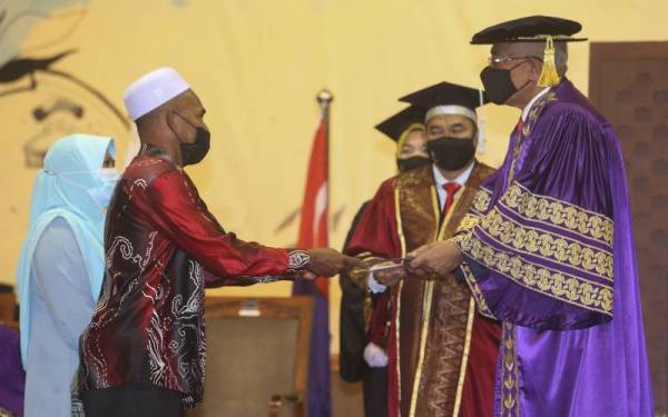 Abd Razak ditemani Najah Aspalila menerima skrol diploma arwah anak mereka, Hanis Nuraishah Nasuha yang disampaikan Mahdzir di Majlis Konvokesyen Kolej Universiti Agrosains Malaysia pada Isnin.