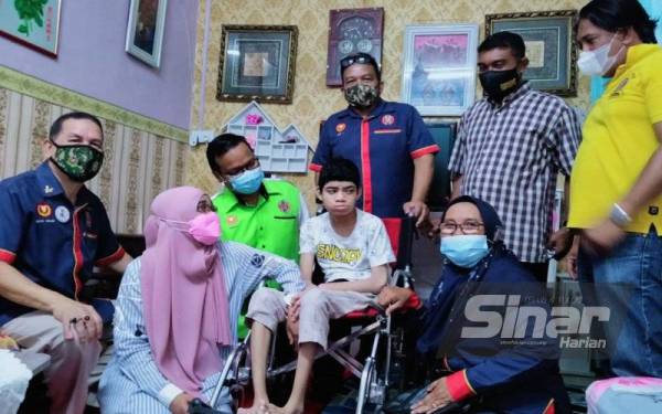 Rohani (dua dari kiri) dan anaknya, Muhammad Syamael mendapat keprihatinan pegawai, anggota, veteran dan rakan arwah yang membuat kutipan bagi membantu menyelesaikan jumlah tunggakan rumah bagi mengelakkan dilelong.