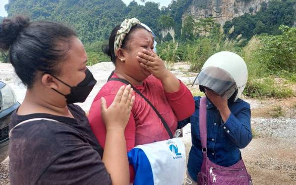 Wak Uda (tengah) ditenangkan oleh ahli keluarganya ketika ditemui di lokasi kejadian runtuhan batu di Simpang Pulai.